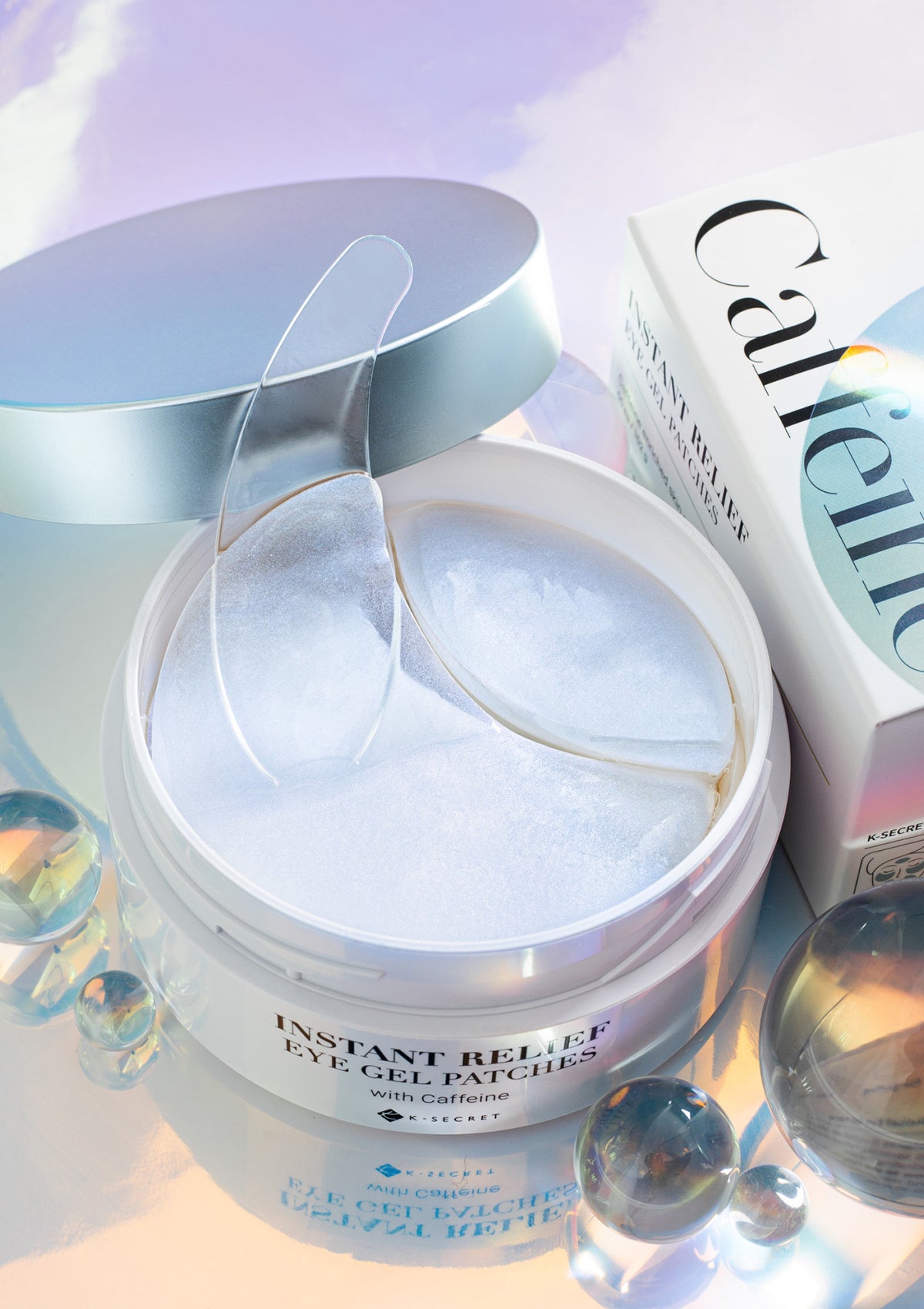 Packaging of K-Secret Instant Relief Eye Gel Patches with Caffeine. The box is predominantly white with a picture of the blue and pink gel patches used for the eyes, and text detailing the product name and key ingredient, Caffeine.